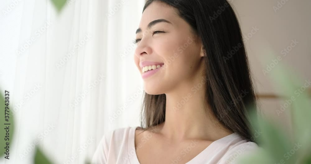 Happy korean woman looking out through window Happy korean woman looking out through window