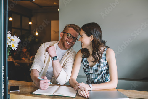 Teacher gently prodding female student with elbow in approval