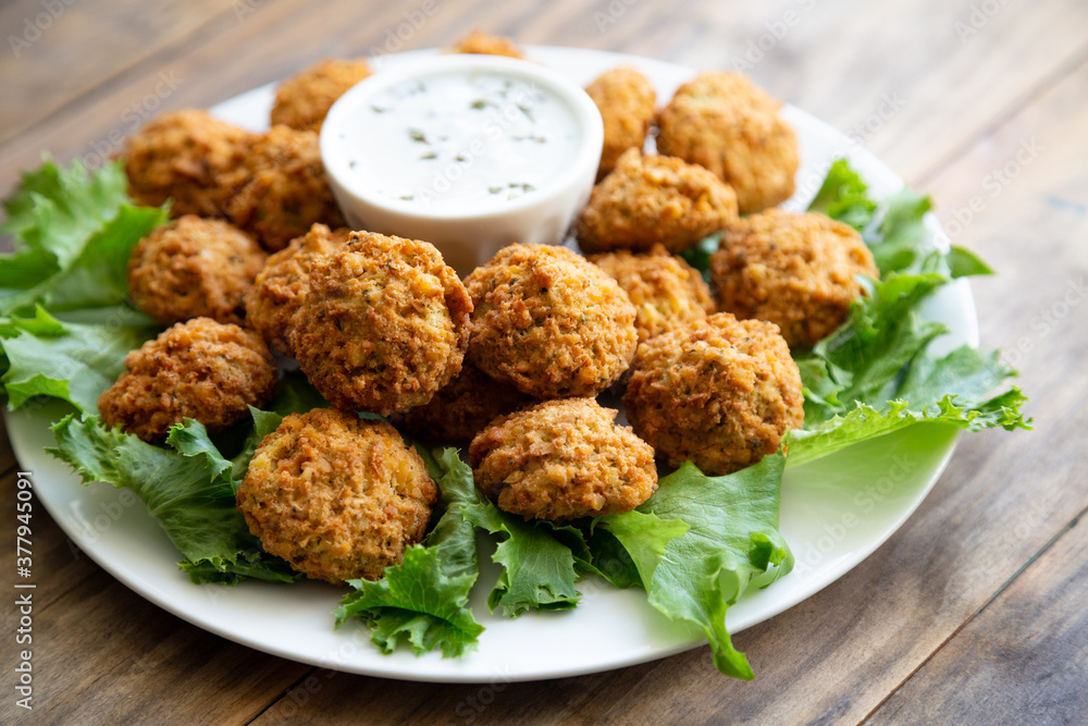 Homemade falafel with yogurt sauce on a wooden table Homemade falafel with yogurt sauce on a wooden table