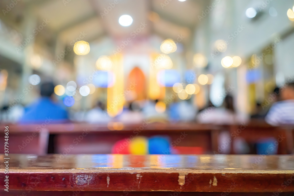 A blurred background photo of the inside of a Vietnamese church sanctuary that is filled with people in the pews, and the pastor stands under a large cross at the altar, in Vietnam.