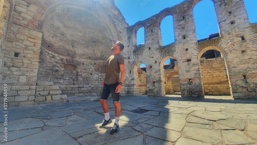 Handsome man standing in a sunlight spot in ancient ruins