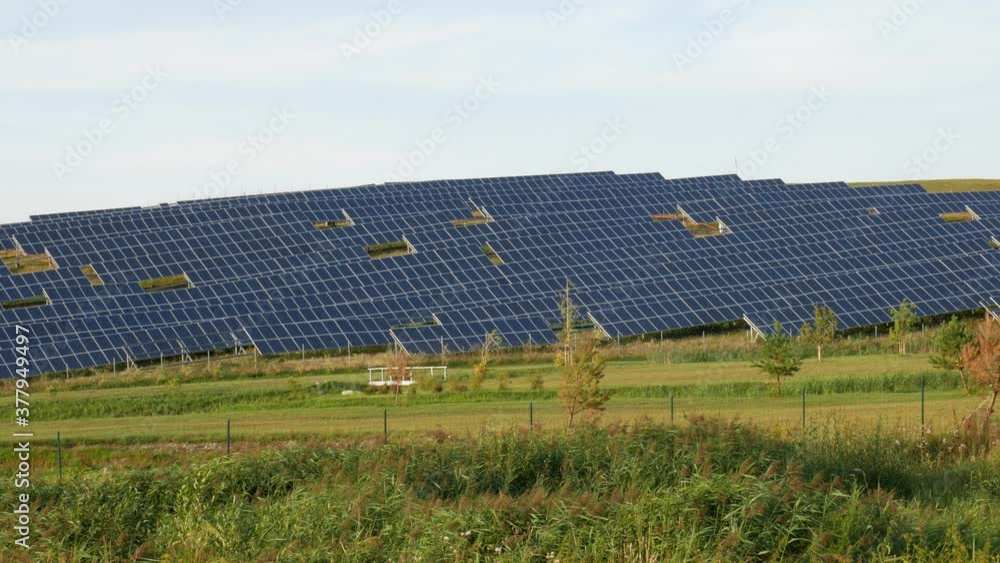 Static shot of solar panel farm situated on hill side while sun rays appears and disappears. Green energy, production, save the planet. Static shot of solar panel farm situated on hill side while sun rays appears and disappears. Green energy, production, save the planet.