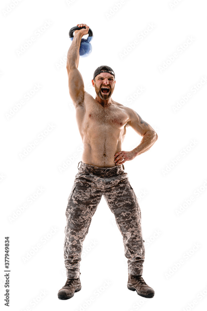 Muscular athlete bodybuilder man in camouflage pants with a naked torso workout with kettlebell on a white background. Isolate Muscular athlete bodybuilder man in camouflage pants with a naked torso workout with kettlebell on a white background. Isolate