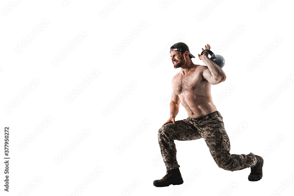 Muscular athlete bodybuilder man in camouflage pants with a naked torso workout with kettlebell on a white background. Isolate Muscular athlete bodybuilder man in camouflage pants with a naked torso workout with kettlebell on a white background. Isolate