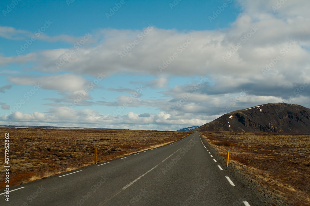 asfaltowa droga na równinie z widokiem na wzgórze 