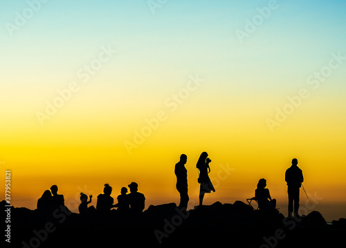 various people at sunset rocky shore