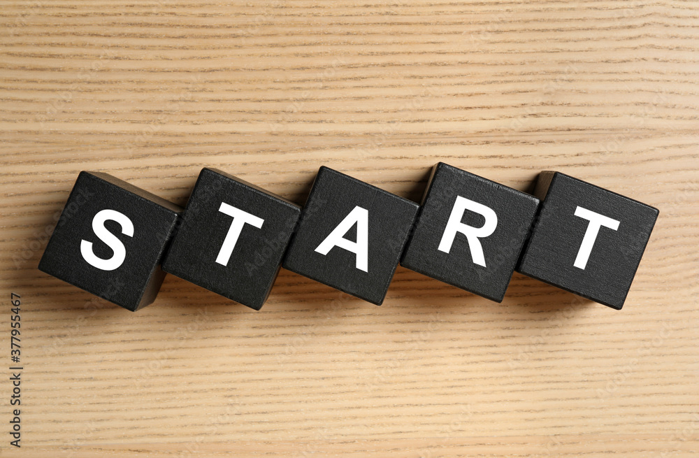 Word START made with black cubes on wooden background, flat lay Word START made with black cubes on wooden background, flat lay