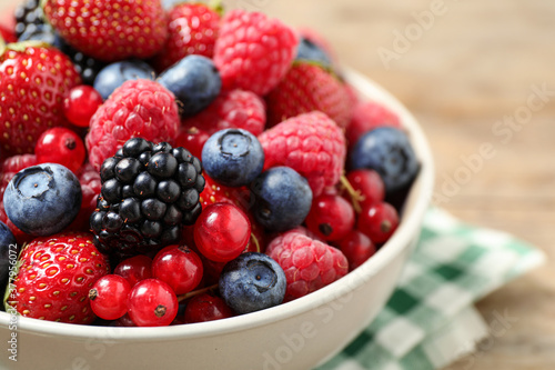 Mix of ripe berries in bowl on table  closeup