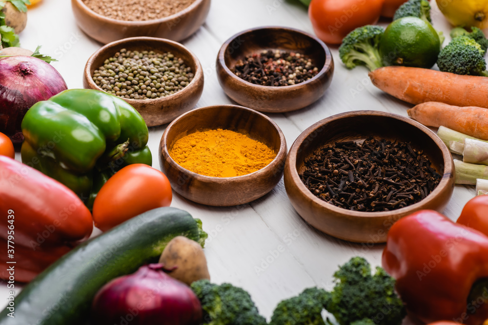 selective focus of fresh ripe vegetables and fruits around bowls with spices on wooden white background selective focus of fresh ripe vegetables and fruits around bowls with spices on wooden white background