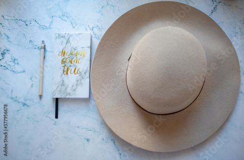 white notebook with pen and hat on marble backgroung photo