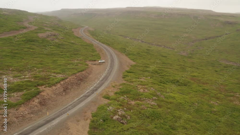 Aerial shot of car driving on winding road through Iceland's desolate Westfjords. Drone shot. Aerial shot of car driving on winding road through Iceland's desolate Westfjords. Drone shot.