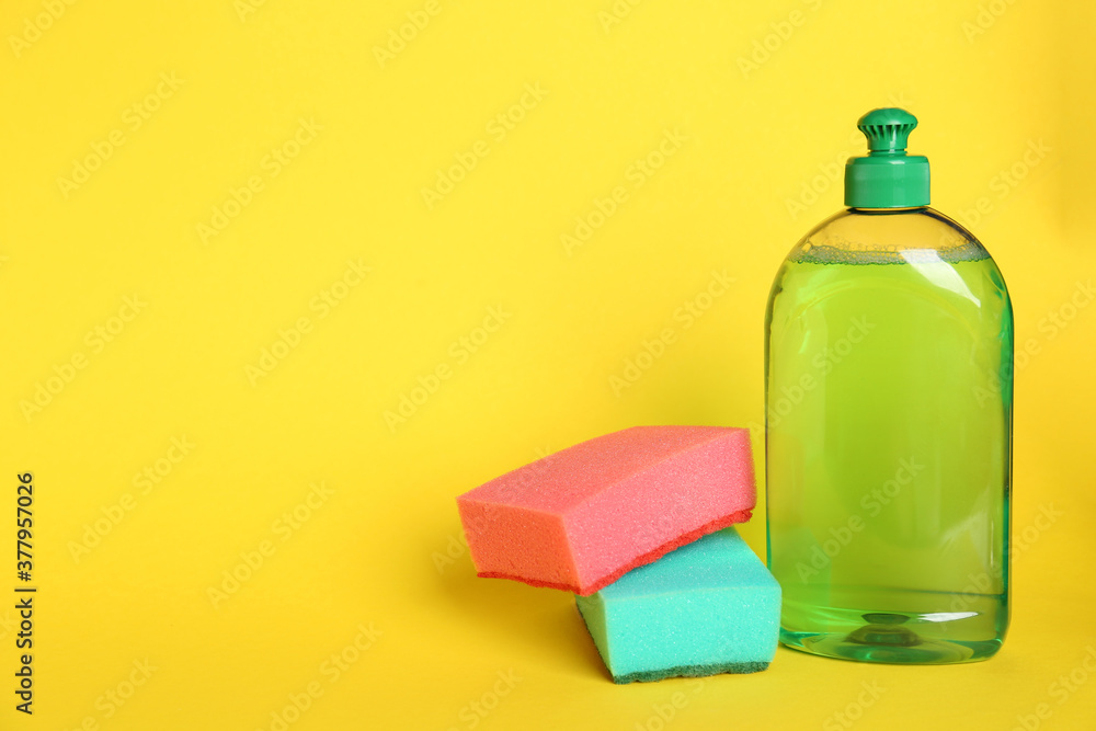 Detergent and sponges on yellow background, space for text Detergent and sponges on yellow background, space for text