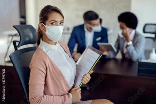 Young woman with protective face mask on a job interview in the office.