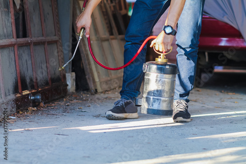 Employees at a termite control company are using a chemical sprayer to get rid of termites at customers' homes and search for termite nests to eradicate them. Chemical spray ideas to prevent insects.