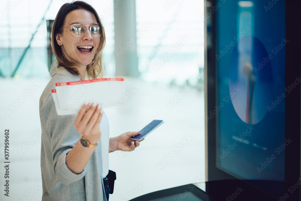 Happy female traveler showing boarding passes standing in airport Happy female traveler showing boarding passes standing in airport