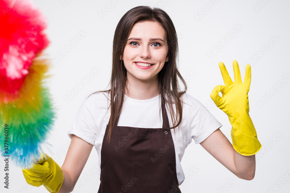 Portrait of a cheerful young housemaid dressed in uniform holding a duster over white background Portrait of a cheerful young housemaid dressed in uniform holding a duster over white background