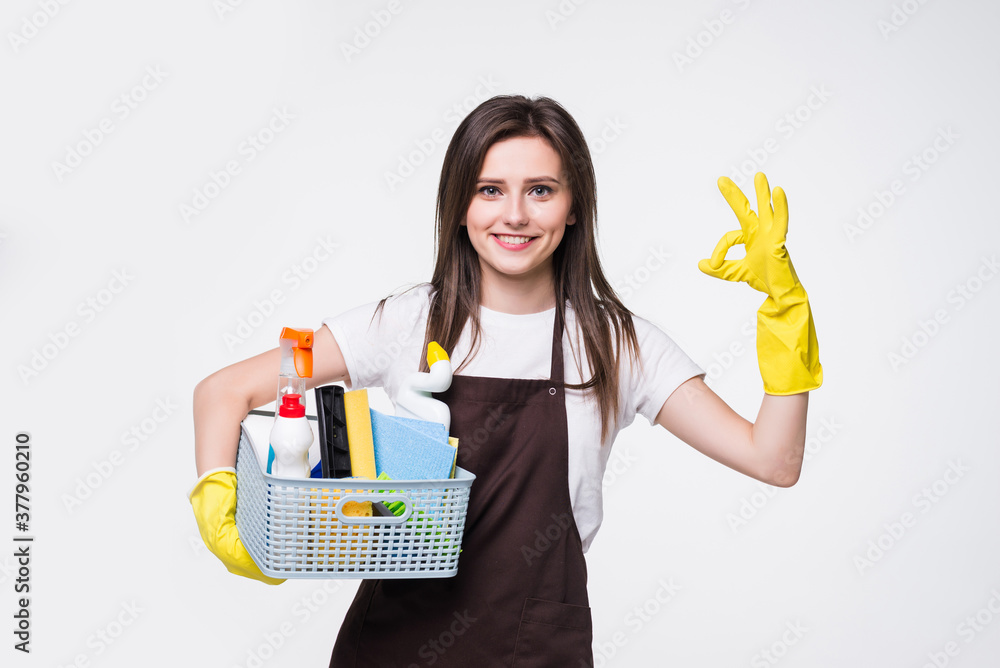 Young woman holding cleaning tools and products in bucket, isolated on white background Young woman holding cleaning tools and products in bucket, isolated on white background
