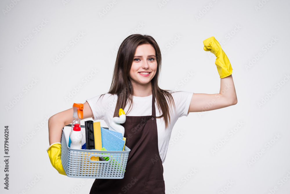 Young woman holding cleaning tools and products in bucket, isolated on white background Young woman holding cleaning tools and products in bucket, isolated on white background