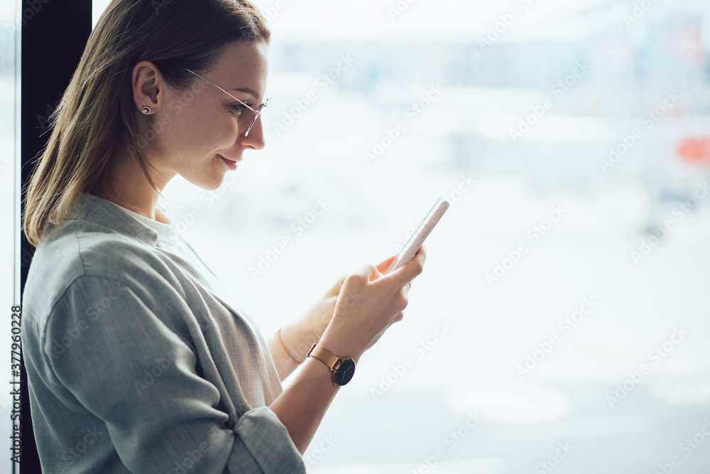 Woman browsing internet on smartphone near glass window