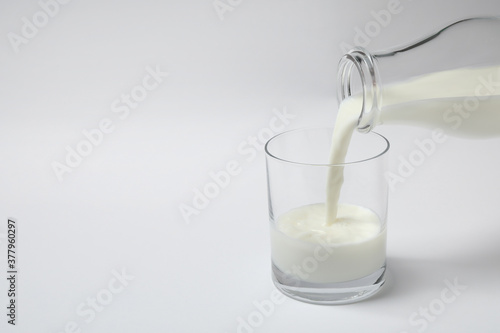 Pouring milk into glass on white background