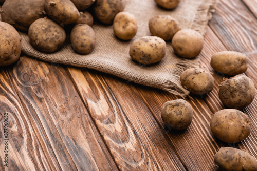 dirty potatoes and burlap on wooden table