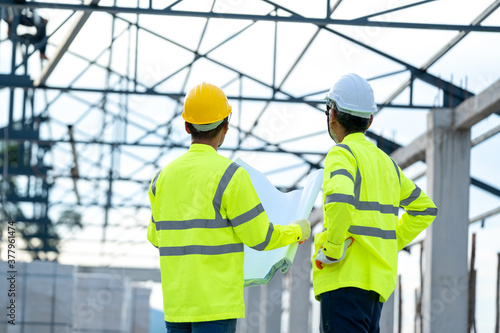 Engineer and architect discussing meeting with blueprint and ideas about building structure on construction site.