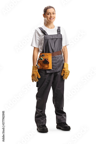 Full length portrait of a repairwoman with a tool belt in a gray uniform