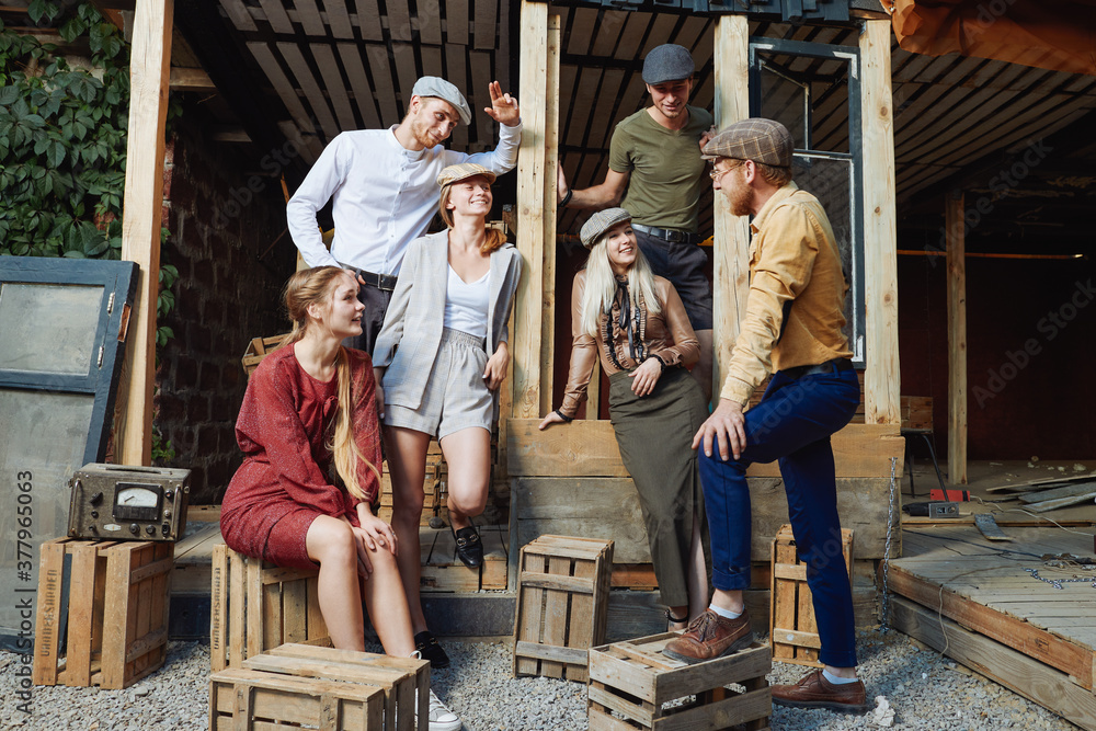 Group of young caucasian people, three girls and three men.They are siting on wooden box .