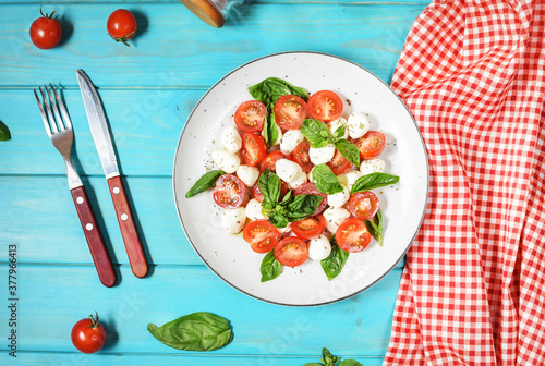Traditional Italian Caprese Salad - sliced tomatoes, mozzarella cheese and basil on wooden background, top view