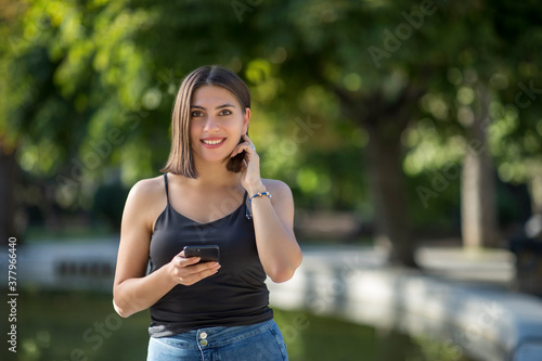 Fototapeta Naklejka Na Ścianę i Meble -  Young beautiful Turkish woman is checking mobile phone while smiling