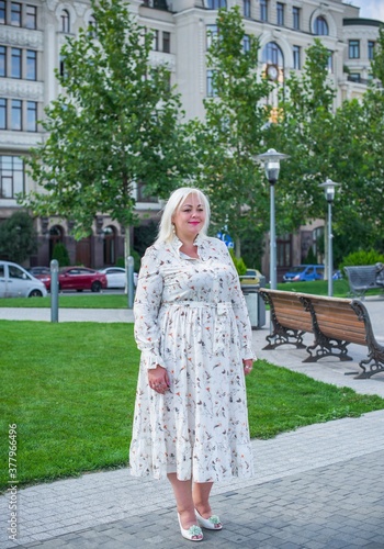 Plus size woman, American or European appearance walks in the city enjoying life. A young lady with excess weight, stylishly dressed in the center of the city. Natural beauty