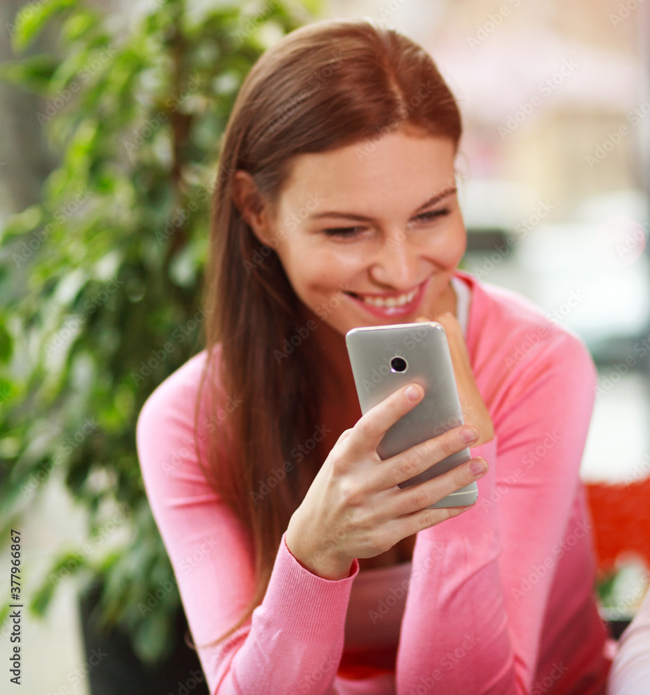 Joyful girl holds online chat on your smartphone, in city cafe, focus on phone Joyful girl holds online chat on your smartphone, in city cafe, focus on phone