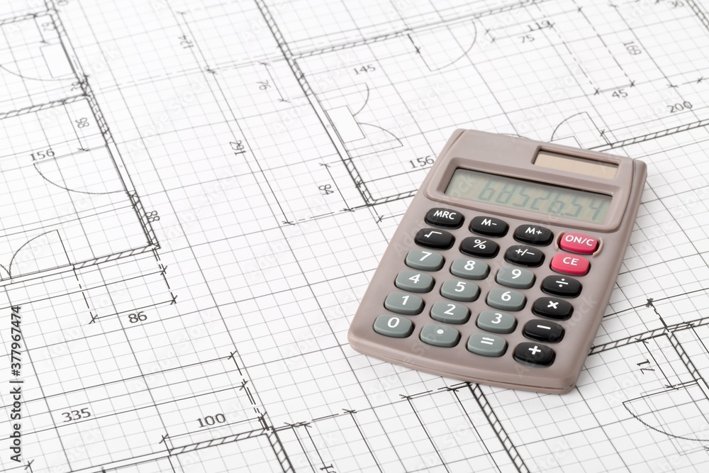 Calculator on architectural house building blueprint plan, real estate or house building costs concept Calculator on architectural house building blueprint plan, real estate or house building costs concept