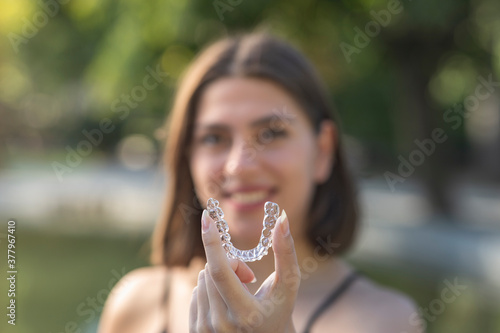 Beautiful smiling Turkish woman is holding an invisalign bracer