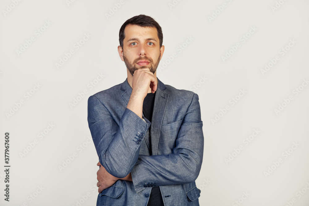Portrait of a young male entrepreneur, looking at the camera with a sad face, a businessman, disappointed by losses in the business. The man looks at the camera, isolated through a gray wall with Portrait of a young male entrepreneur, looking at the camera with a sad face, a businessman, disappointed by losses in the business. The man looks at the camera, isolated through a gray wall with