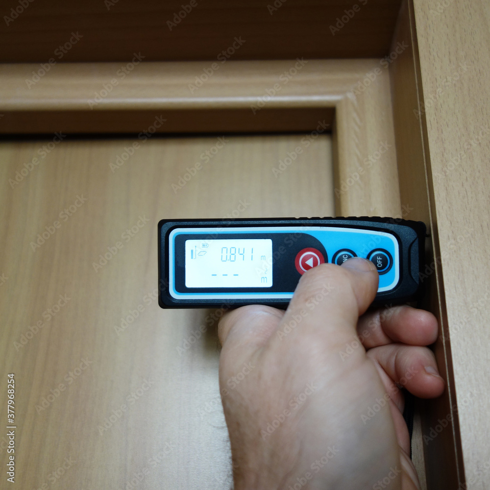 the builder measures the door opening with a laser ruler. construction and renovation concept the builder measures the door opening with a laser ruler. construction and renovation concept