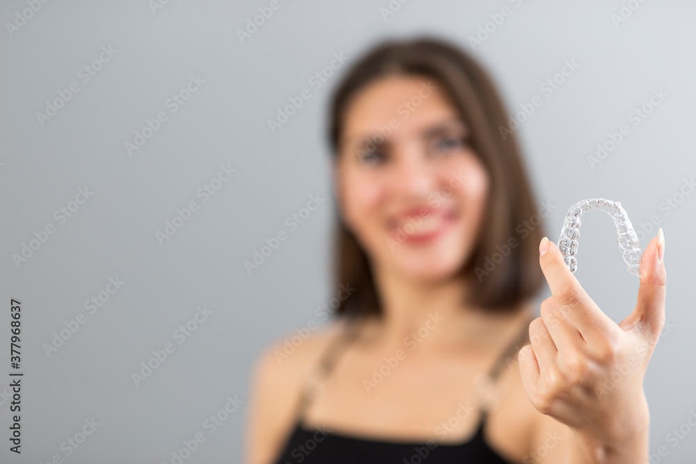 Beautiful smiling Turkish woman is holding an invisalign bracer, Isolated studio shot with copy space Beautiful smiling Turkish woman is holding an invisalign bracer, Isolated studio shot with copy space