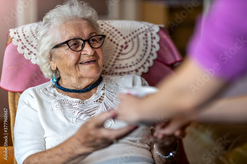 Helpful home healthcare nurse gives a senior female a cup of hot tea
 photo