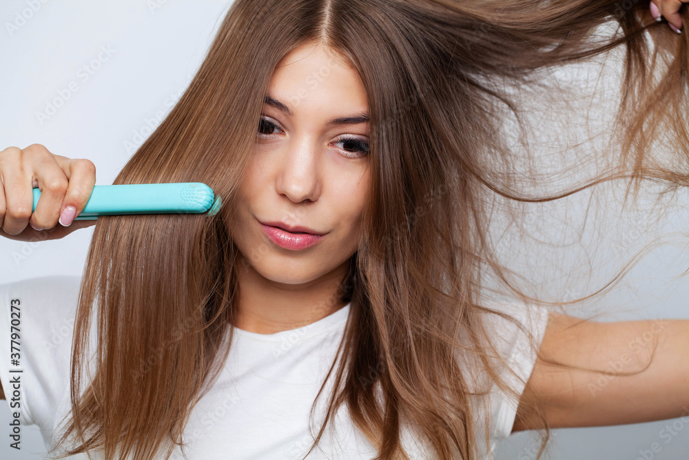 Woman With Beautiful Long Straight Hair Using Hair Straightener Woman With Beautiful Long Straight Hair Using Hair Straightener