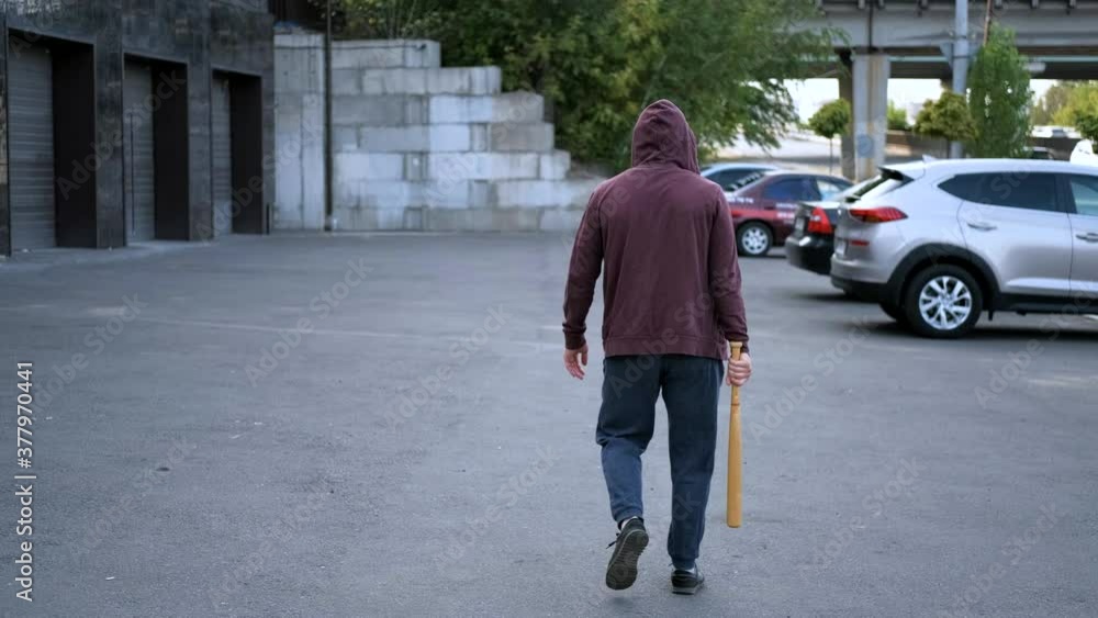 robber vandal with a bat goes along the cars and is plotting something robber vandal with a bat goes along the cars and is plotting something
