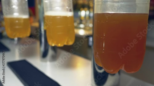 draft beer of different varieties is poured from taps into plastic bottles photo