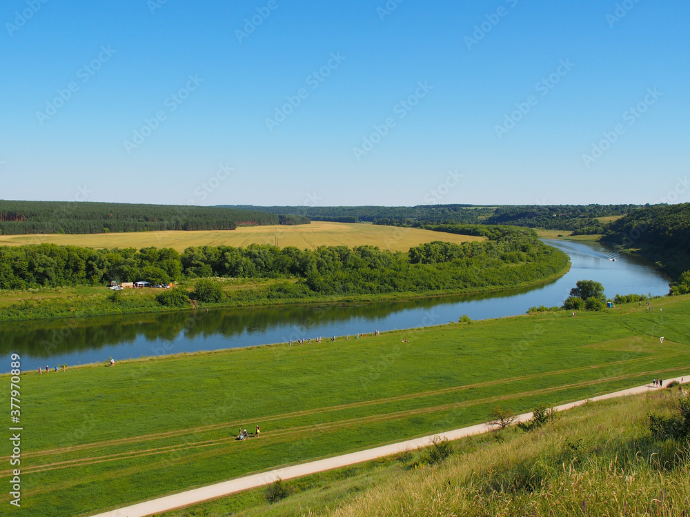 Green grass, river, field and blue sky. Copy space for text.
