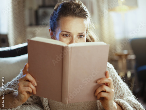 young woman in modern house in sunny autumn day reading book photo