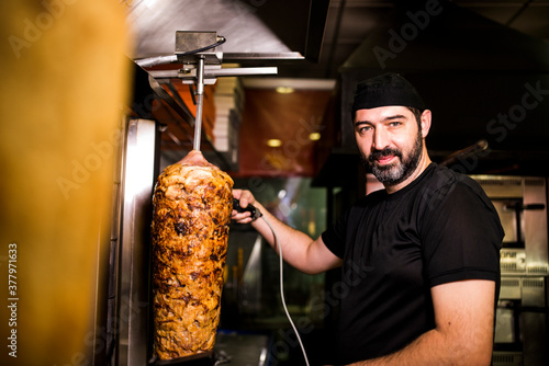 Photos Bearded man preparing kebab meat in pizza bar.