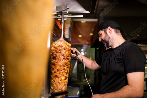 Bearded man preparing kebab meat in pizza bar. photo