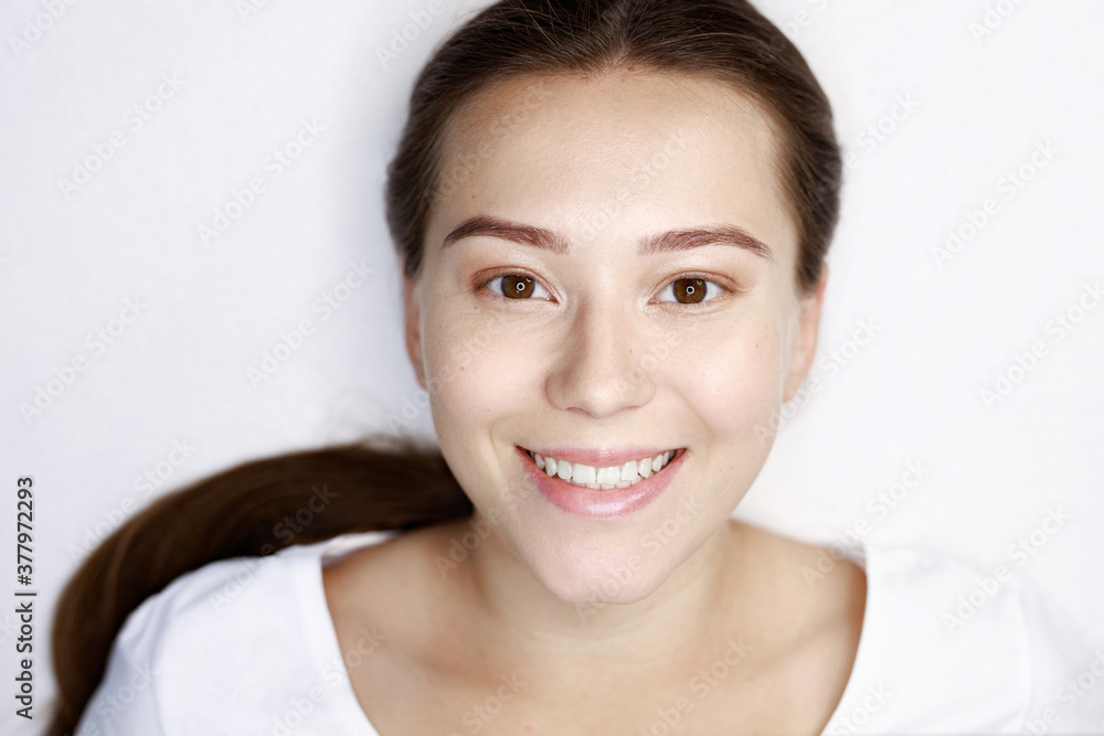 Beautiful young girl on white background. Portrait of happy smiling woman. Female with healthy glow smooth skin. Beautiful young girl on white background. Portrait of happy smiling woman. Female with healthy glow smooth skin.