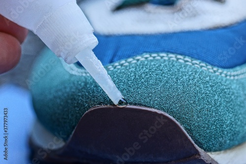 white tube in hand glue the sock of a suede and leather sneaker photo