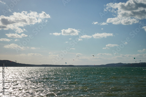 View of a beautiful lake in Bavaria, water athletes are practicing their hobby wind surfing and kite boarding, blue sky and bright sunlight. Germany, Brombachsee.