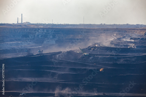 Open pit extraction of coal in quarry "Bogatyr", Ekibastuz, Kazakhstan. Quarry truck and excavators. Ekibastuz Power Station on background.