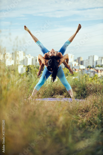 Two strong women doing acroyoga outdoors.